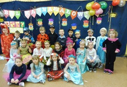 Dzieci z grupy Misie (Jarogniewice) na zdjęciu grupowym podczas balu karnawałowego. Dzieci są przebrane w stroje karnawałowe. W tle kolorowa dekoracja. (photo)