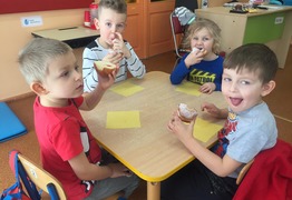 Dzieci z grupy Mądrale (Borówko Stare) podczas świętowania dnia Tłusty Czwartek. Dzieci siedzą przy stolikach i jedzą pączki (photo)