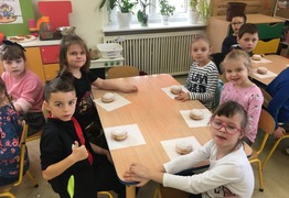Dzieci z grupy Kangusie (Ul. Nowa) podczas świętowania dnia Tłusty Czwartek. Dzieci siedzą przy stolikach i jedzą pączki (photo)