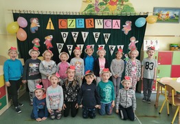Dzieci z grupy Kangurki  na zdjęciu grupowym. W tle gazetka przygotowana z okazji Dnia Dziecka. Dzieci mają na głowach kolorowe opaski (photo)