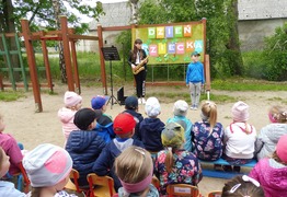 Dzieci z grupy Misie i Zajączki podczas koncertu saksofonowego z  okazji Dnia Dziecka. W tle kolorowa dekoracja z napisem  (photo)